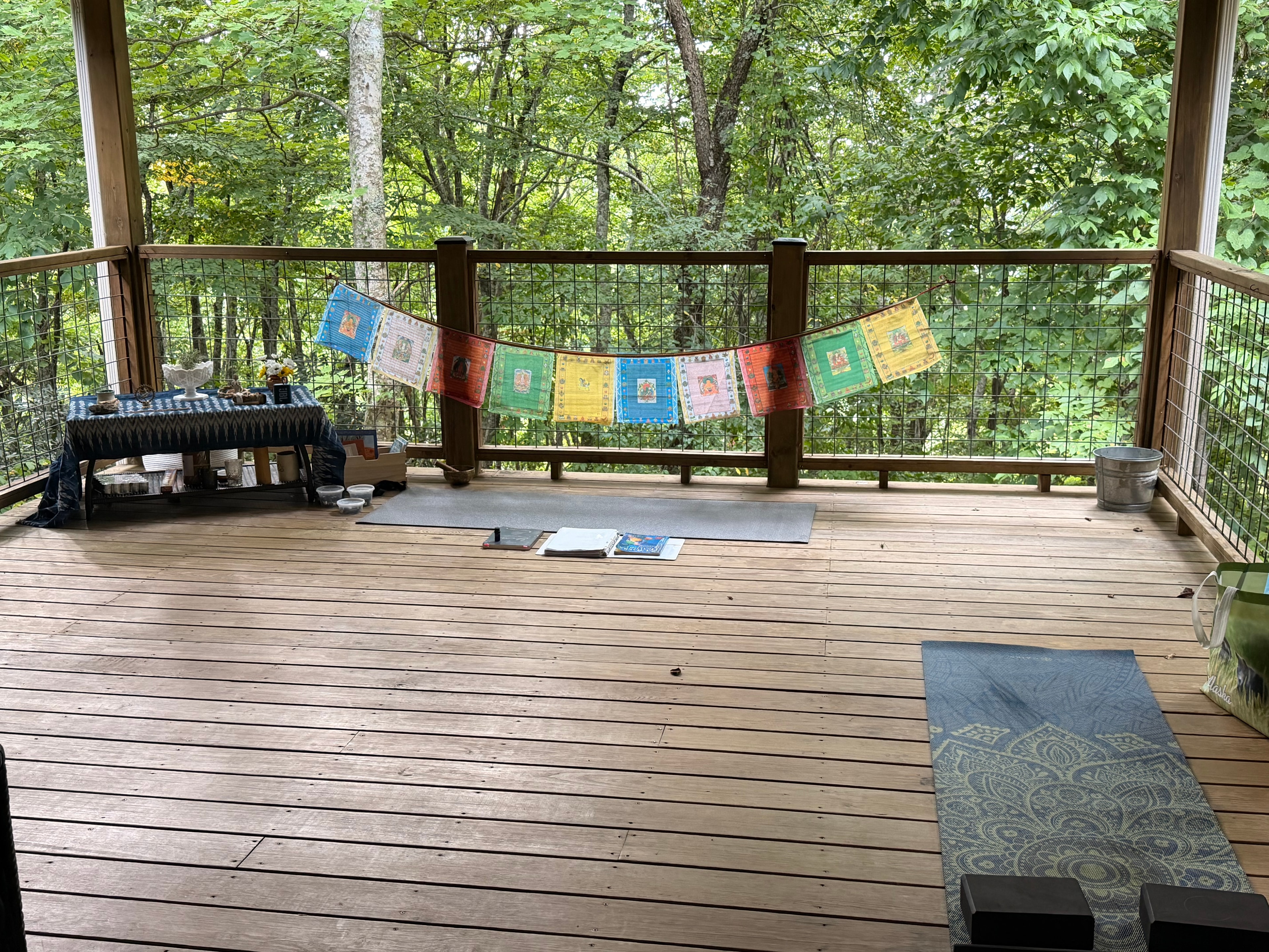 Retreat deck with colorful prayer flags and forest views